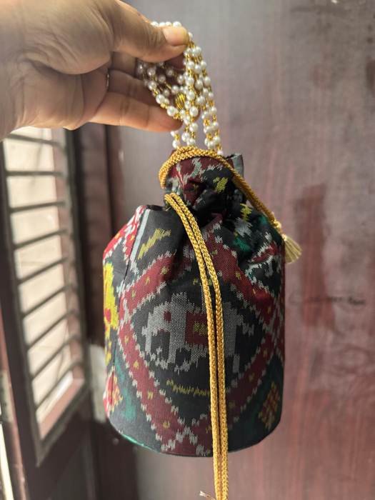 A Bawariyo potli held in hand, showing pearl-strand handles